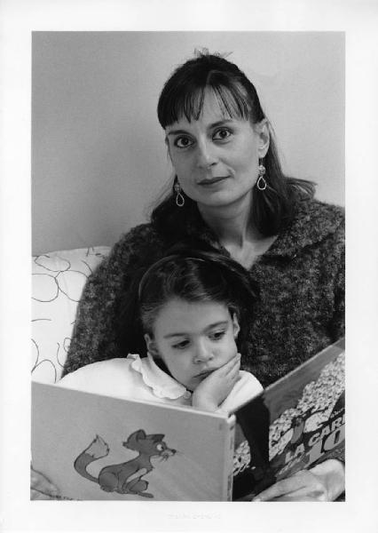 Ritratto di coppia. Madre e figlia. Bambina legge un libro. Divano