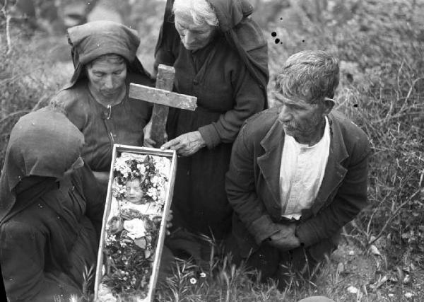 Italia del Sud. Calabria - Isca - Terremoto - Funerali di un neonato - Ritratto di gruppo: tre donne e un uomo, neonato in una bara - Croce