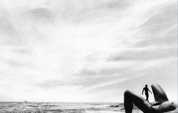 Donna in topless sulla spiaggia - un uomo all'orizzonte