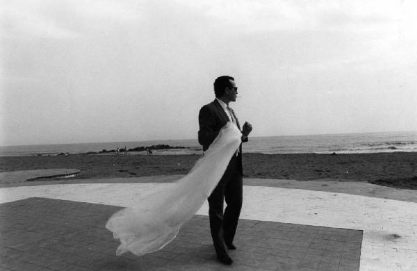 Castel Volturno. Uomo con velo da sposa passeggia in riva al mare