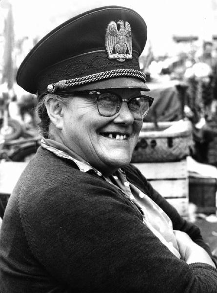 Fiera di Sinigaglia. Milano - Mercatino - Ritratto femminile - Anziana rigattiere con cappello militare, occhiali, sorriso sdentato