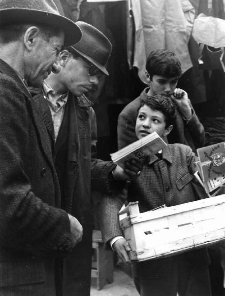 Fiera di Sinigaglia: Bimbi. Milano - Mercatino - Ritratto di gruppo - Bambino con cassetta di legno, venditore ambulante libri usati e uomini