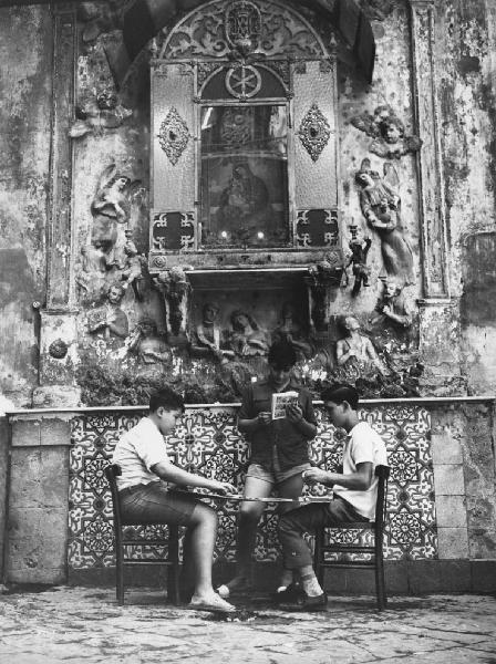 Napoli: Scugnizzi, si gioca. Napoli - Vicoli - Ritratto di gruppo - Ragazzo in piedi e due ragazzi seduti sotto un'edicola, cappella votiva della Madonna - Lettura - Gioco delle carte