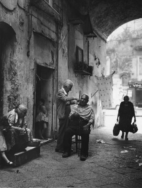 Napoli: Lavoro. Napoli - Vicoli - Anziano barbiere al lavoro: taglio di capelli
