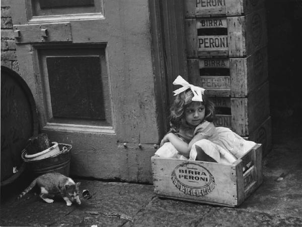 Napoli: Scugnizzi, passatempi/ Scene di vita varie. Napoli - Vicoli - Ritratto infantile: bambina in una scatola di legno della birra Peroni - Gatto - Gioco