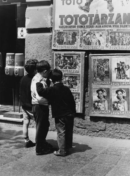 Napoli: Scugnizzi, si gioca. Napoli - Vicoli - Bambini fuori da un cinema guardano i manifesti del film Tototarzan