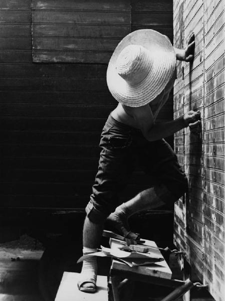 Napoli: Lavoro. Napoli - Ritratto maschile - Uomo a torso nudo con jeans, zoccoli e cappello di paglia su una scala - Lavori domestici: manutenzione serratura di una porta