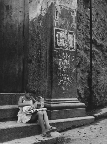 Napoli: Bimbi, soli. Napoli - Strada - Ritratto infantile - Bambina seduta sui gradini con giornale - Gioco - Scritte d'amore sul muro con cuore