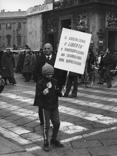 Piazza Duomo: Scritti. Milano - Piazza del Duomo - Arengario - Manifestazione - Bambino con cartellone con scritta politica socialista - Uomini sullo sfondo