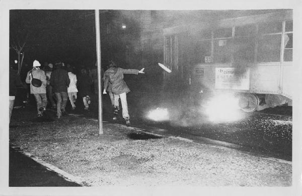Manifestazioni Italia anni '70. Milano - Scontri all'inaugurazione della prima del Teatro alla Scala, Otello - Gruppo di manifestanti in fuga - Tram - Incendio