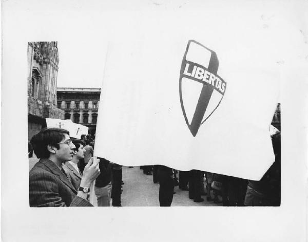 Italia: manifestazioni democristiane. Milano - Piazza del Duomo - Manifestazione politica - Ritratto maschile - Ragazzo con bandiera del partito Democrazia Cristiana D. C