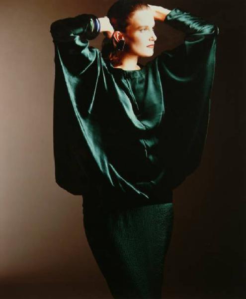 Campagna pubblicitaria per Trussardi Donna - Modella con mani sulla testa: casacca di raso verde con maniche a pipistrello, gonna e orecchini metallici