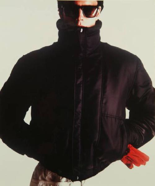 Campagna pubblicitaria per Trussardi Uomo - Modello con mani in tasca: giacca a vento nera su pantaloni chiari, guanti rossi e occhiali da sole