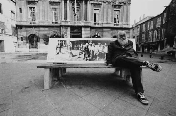 Anziano seduto su una panchina in una piazza cittadina