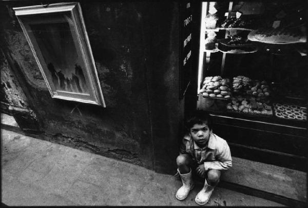 Firenze - Ritratto infantile: bambino seduto davanti a una vetrina di dolciumi