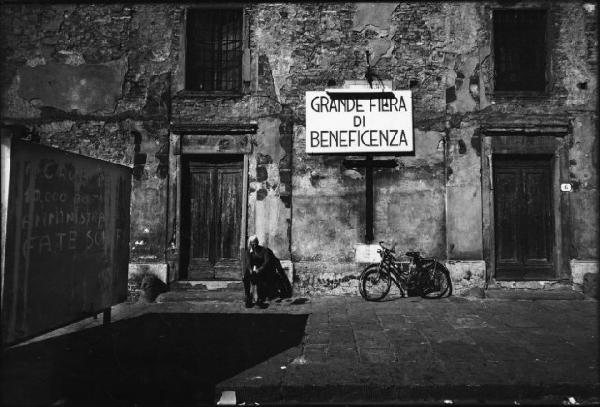 Firenze: Peretola - Strada - Ritratto maschile: anziano seduto - Cartello con scritta "grande fiera di beneficenza" - Bicicletta