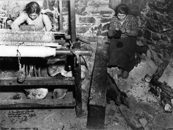 Africo. Donna tesse al telaio e donna lavora maglia ad aghi. Galline e maiale