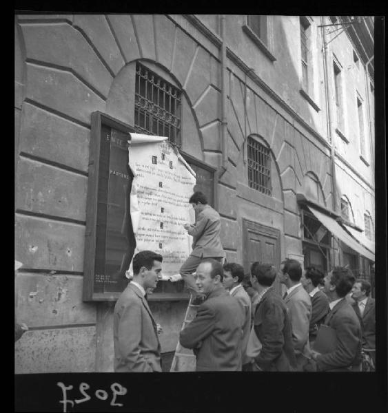 Mantova - Gruppo di studenti universitari - Studente nell'atto di affiggere un manifesto sulla bacheca di un edificio