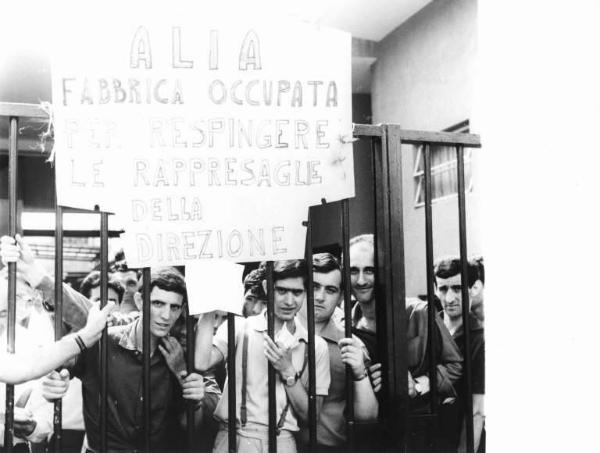 Alia - Occupazione della fabbrica contro le rappresaglie padronali e i licenziamenti - Lavoratori dietro i cancelli - Cartello di denuncia