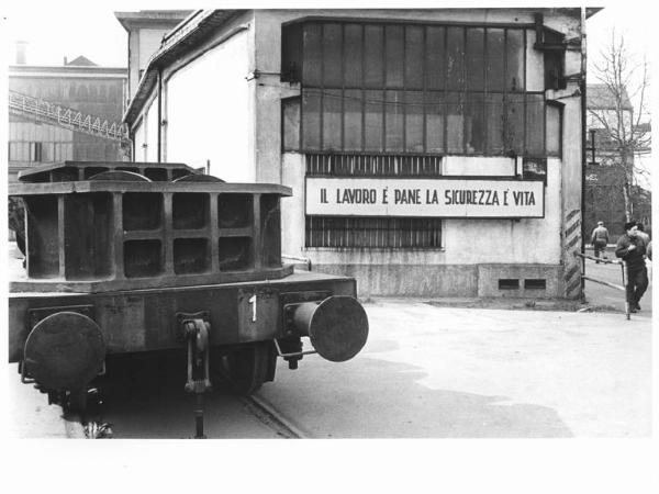 Falck Unione - Cortile - Capannone con scritta "Il lavoro è pane, la sicurezza è vita" - Locomotore