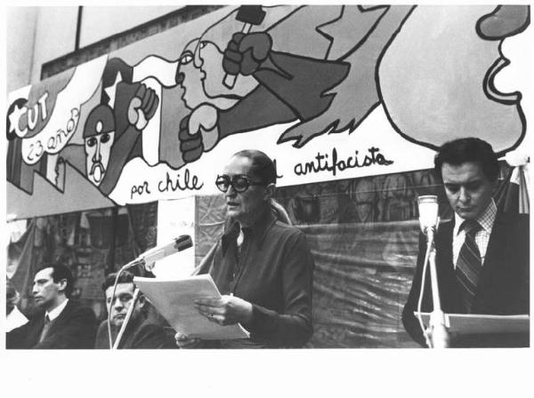 Castello Sforzesco - Sala della Balla - Interno - Manifestazione a sostegno del Cile antifascista - Tavolo della presidenza con Lucio De Carlini e Lauro Casadio - Oratrice al microfono - Pannello dipinto a mano