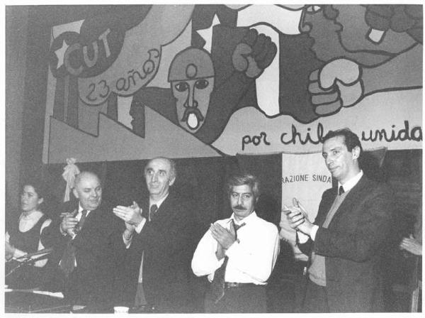 Castello Sforzesco - Sala della Balla - Interno - Manifestazione a sostegno del Cile antifascista - Tavolo della presidenza - Oratori in piedi applaudono, tra gli altri G. Polotti, M. Pirola e L. De Carlini - Pannello dipinto a mano - Bandiera