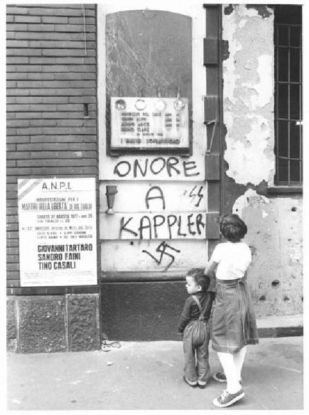 Via Tibaldi - Lapide partigiana dei martiri della libertà - Scritte fasciste inneggianti a Kappler - Manifesto dell'Anpi - Bambini osservano la lapide