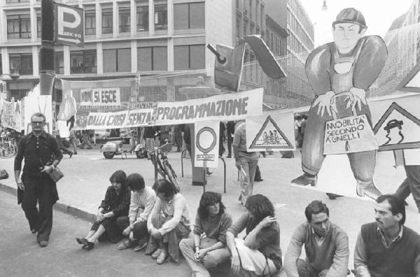 Sciopero dei lavoratori di diverse fabbriche contro i licenziamenti, per l'occupazione - Presidio davanti alla sede dell'Assolombarda - Donne sedute sul marciapiede - Striscione