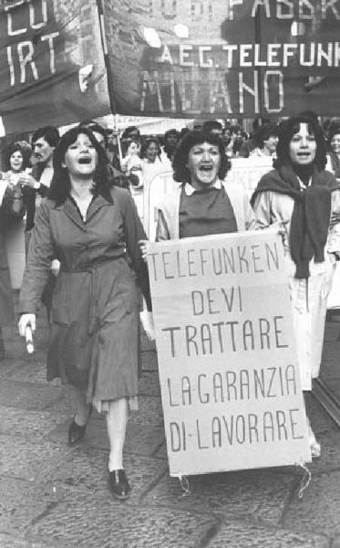 Sciopero delle lavoratrici della Irt Firt Telefunken - Corteo - Ritratto femminile - Operaie con grembiule da lavoro urlano slogan - Cartello - Striscione