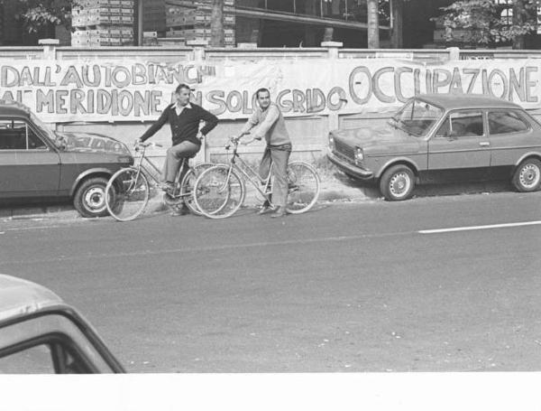 Fabbrica Autobianchi - Picchetto dei lavoratori davanti alla portineria contro i licenziamenti alla Fiat - Passanti in bicicletta - Striscioni