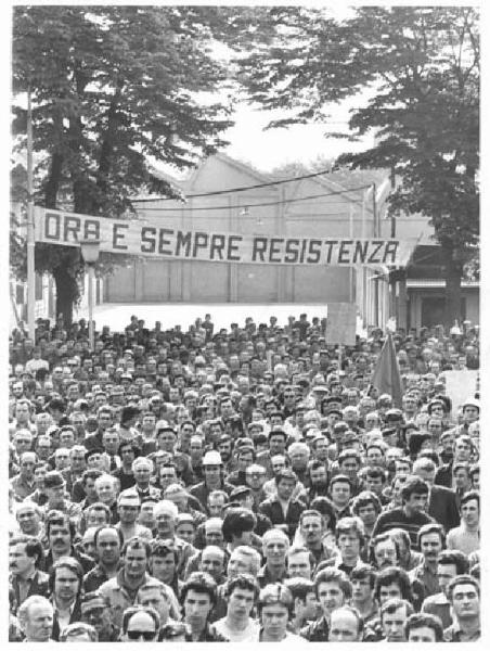 Falck - Celebrazione del 30° anniversario della Liberazione - Comizio nel cortile della fabbrica - Folla di operai - Striscione "Ora e sempre resistenza" - Bandiera