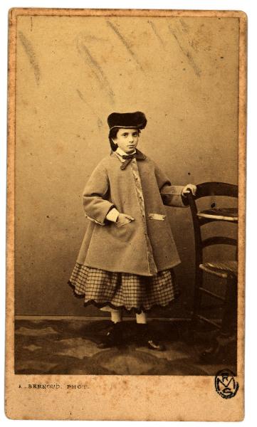 Ritratto infantile - Bambina con soprabito, cappello e gonna a quadri
