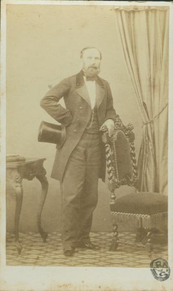 Ritratto maschile - G. Kaiser, in piedi, con un cappello a tuba e il braccio sinistro appoggiato allo schienale di una sedia