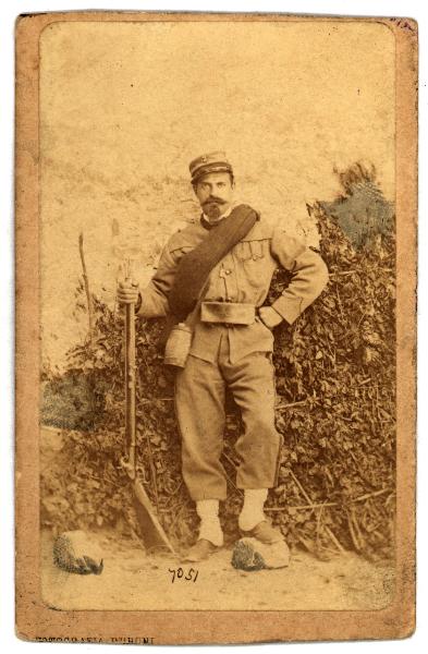 Ritratto maschile - Militare- Uomo in uniforme con fucile tra finti arbusti