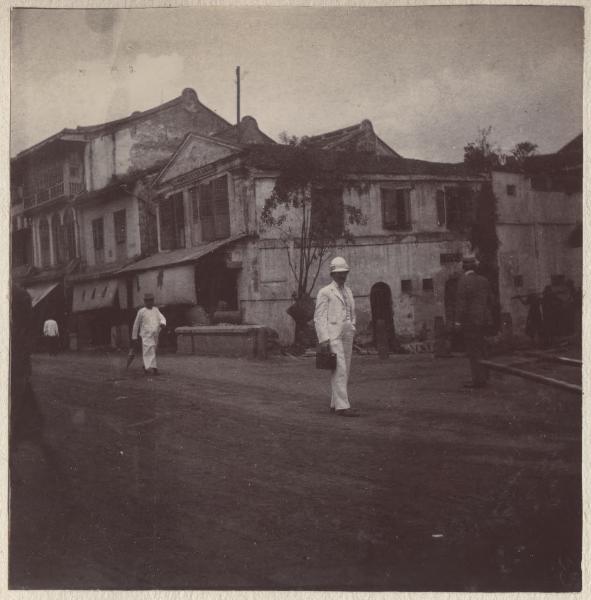 Repubblica di Singapore - Strada della città - Un uomo in completo coloniale bianco con caschetto passeggia tra le case