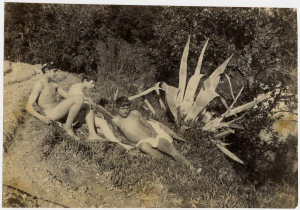 Tre nudi maschili seduti, sullo sfondo una pianta di agave