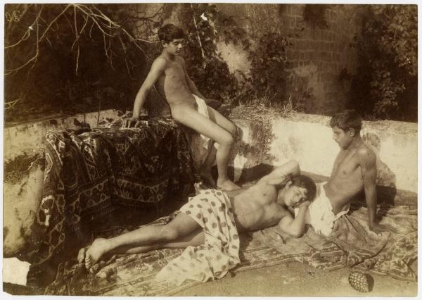 Tre nudi maschili drappeggiati, due seduti e uno sdraiato su un tappeto