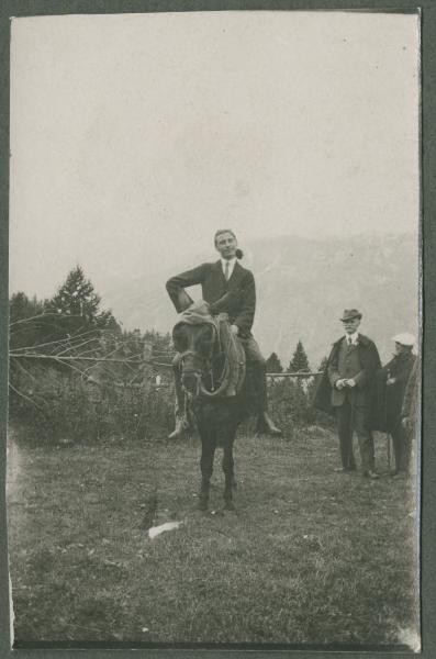 Ritratto maschile - Uomo in sella a un cavallo - Uomini in secondo piano - Esterno - Prato