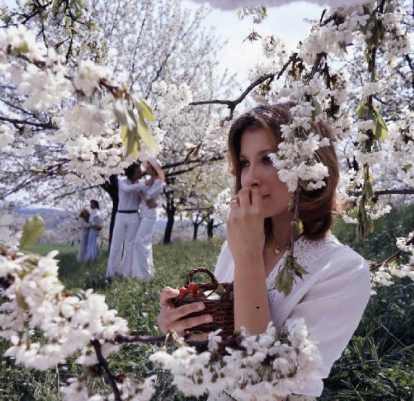 Campagna pubblicitaria Mon Chéri. Alberi di ciliegio in fiore - giovane donna con cestino di ciliegie - coppie