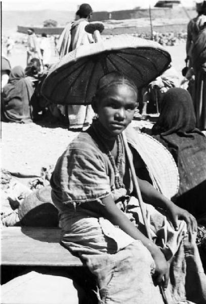 Viaggio in Africa. Ritratto femminile - giovane venditrice ambulante al mercato di Macalle si ripara dal sole con ombrellino artigianale