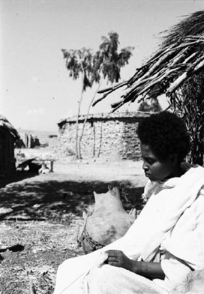 Viaggio in Africa. Ritratto femminile - donna indigena ripresa di profilo. Sullo sfondo delle mura in pietra