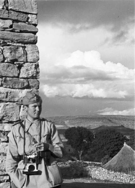 Viaggio in Africa. Soldato italiano appoggiato a pilastro in pietra, con paesaggio sullo sfondo