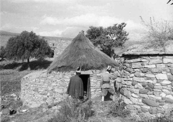 Viaggio in Africa. Quiha: scorcio del villaggio, una capanna in pietra con tetto di paglia e militari indigeni in perlustrazione