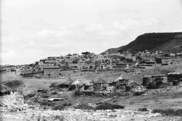 Viaggio in Africa. Paesaggio africano: villaggio con capanne in pietra dai tetti di paglia, muretti a secco ed edifici in pietra
