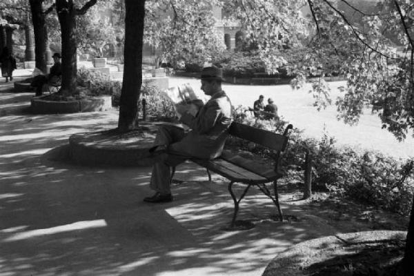 Viaggio in Jugoslavia. Zagabria: un viale alberato e un uomo che legge seduto su una panchina