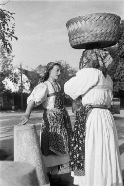 Viaggio in Jugoslavia. Sestine: due donne croate che conversano. Un reca una cesta di vimini in testa