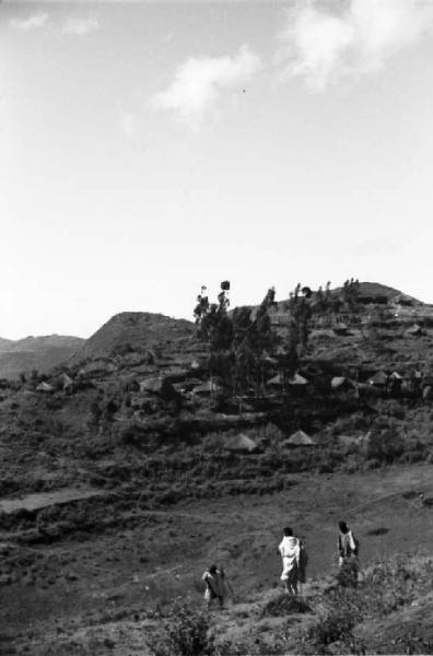 Viaggio in Africa. Paesaggio africano: veduta - alcuni uomini africani e sullo sfondo capanne con tetti di paglia