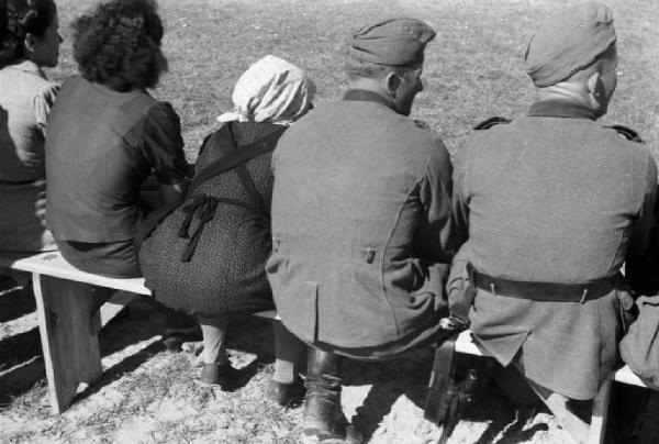 Viaggio in Jugoslavia. Domenica sportiva a Sisak: gruppo di persone, tra cui un soldato Ustascia, seguono una partita di calcio dal bordo del campo