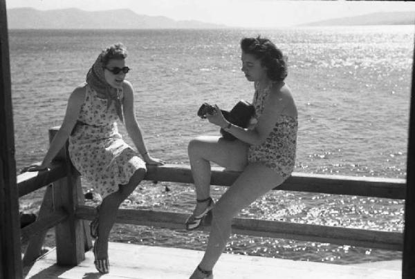 Viaggio in Jugoslavia. Due giovani donne in riva al mare - una suona la chitarra
