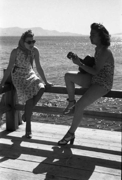 Viaggio in Jugoslavia. Due giovani donne in riva al mare - una suona la chitarra